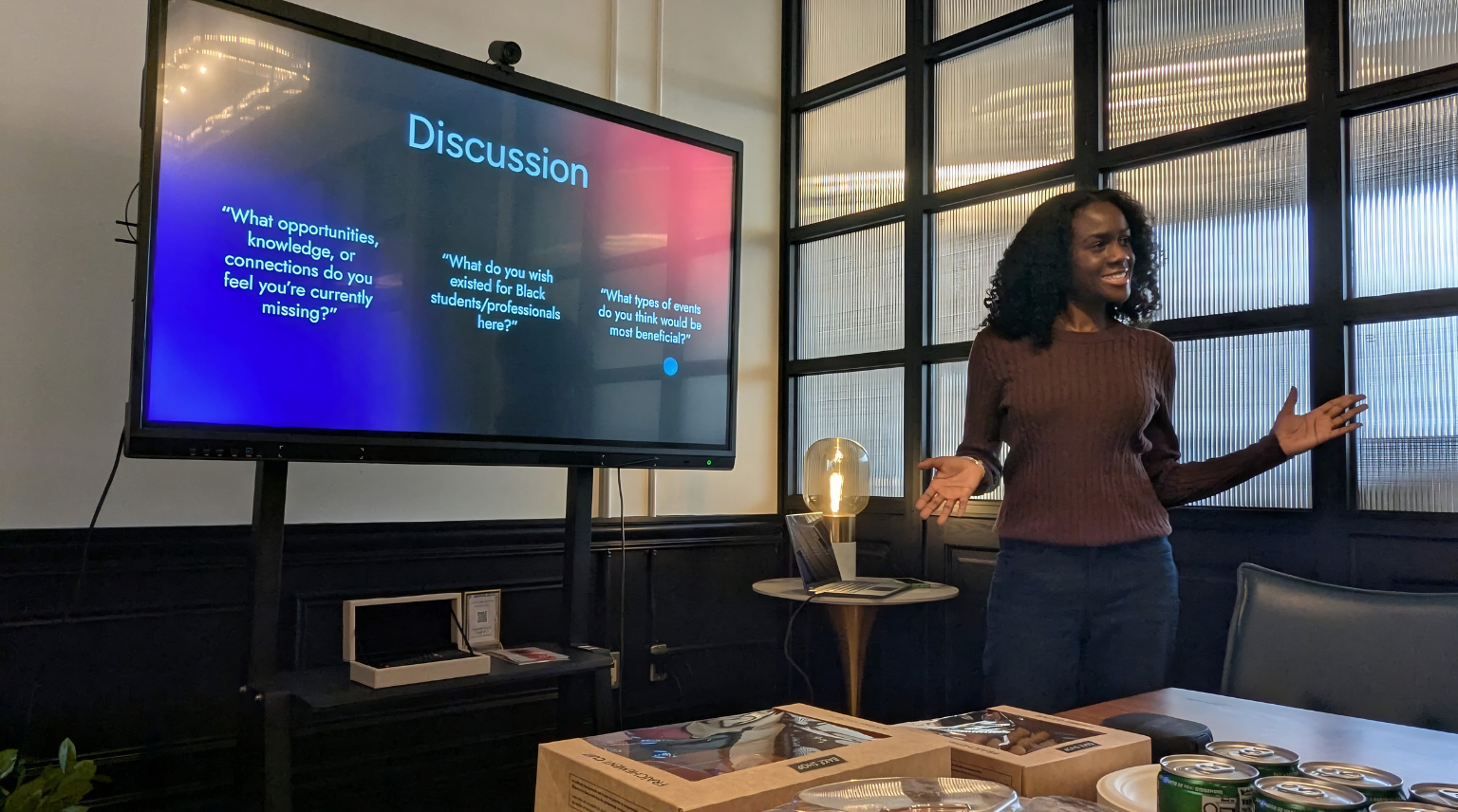 Woman presenting in front of a screen with 'Discussion' on it in an office setting.
